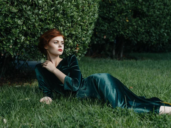 Ελκυστική γυναίκα σε πράσινο φόρεμα βρίσκεται στο γκαζόν γοητεία διακόσμηση φαντασία — Φωτογραφία Αρχείου