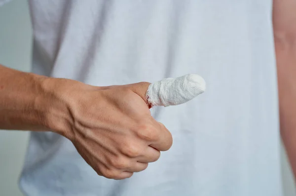 Homem doente em uma camiseta branca com uma mão enfaixada fundo isolado — Fotografia de Stock