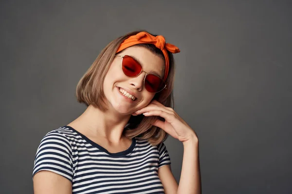 Donna in occhiali da sole con una benda arancione sulla testa in una t-shirt a righe — Foto Stock