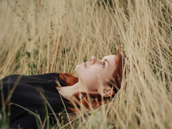 Mulher em um vestido preto encontra-se na grama natureza liberdade resto — Fotografia de Stock