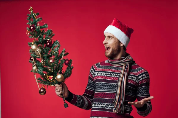 Yeni yıl kıyafetleri içinde bir adam Noel ağacı elinde oyuncaklar tatil duyguları — Stok fotoğraf