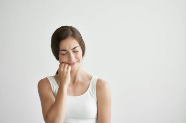 Kafasını tutan beyaz tişörtlü kadın baş ağrısı, yaşam tarzı bunalımı