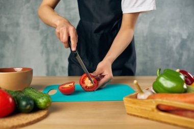 Mutfakta siyah önlüklü aşçı Sebze kesme tahtası