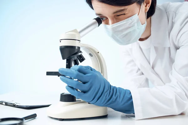 Γυναίκα γιατρός κοιτάζοντας μέσα από ένα μικροσκόπιο εργαστήριο βιοτεχνολογίας έρευνα — Φωτογραφία Αρχείου