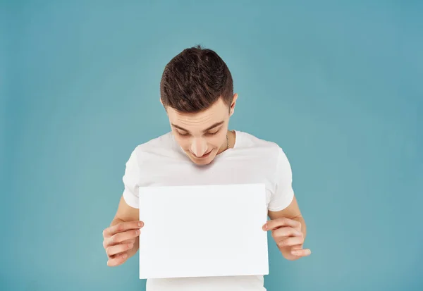 Man in wit t-shirt met wit vel papier in zijn handen Kopieer ruimte — Stockfoto