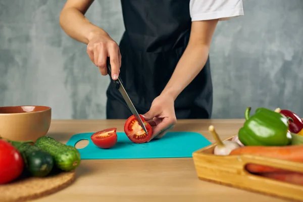 Cuire en tablier noir sur la planche à découper de légumes de cuisine — Photo