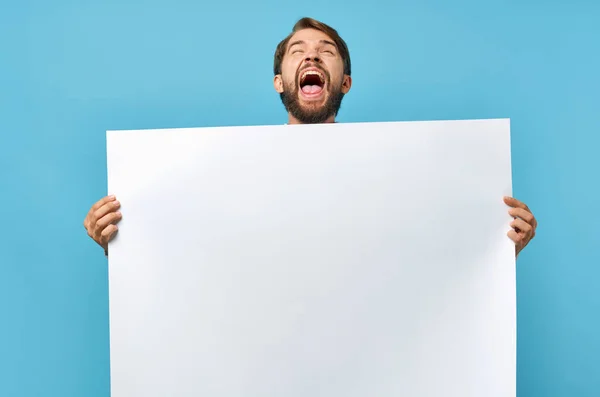 Man met baard witte banner in de hand blanco blad presentatie blauwe achtergrond — Stockfoto