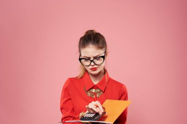 Kırmızı tişörtlü, elinde not defteri olan bir kadın profesyonel olarak çalışıyor.