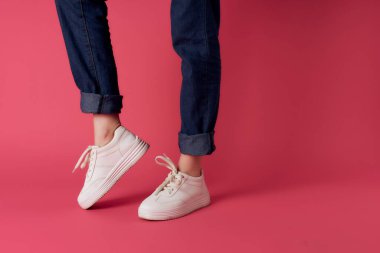 Beyaz spor ayakkabılı ters kadın bacakları pembe arka plan kırpılmış görüntü stüdyosu