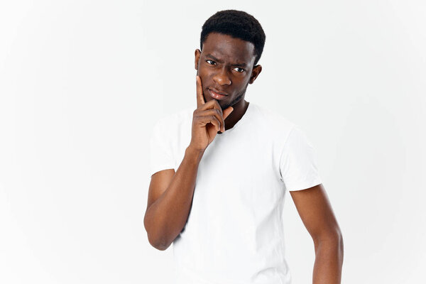 Cute guy african appearance on a light background cropped view of a white t-shirt model. High quality photo