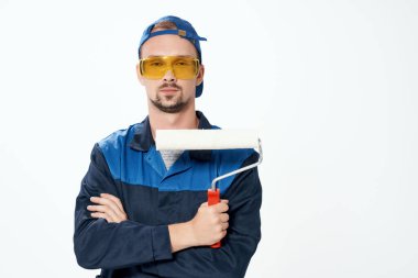 Çalışan üniformalı bir adam elleriyle duvarları boyayan bir silindir.