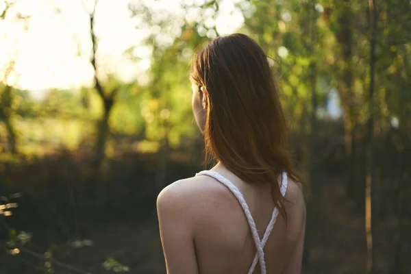 하얀 드레스를 입고 숲 속 나무를 타고 여름 산책하는 여성 — 스톡 사진