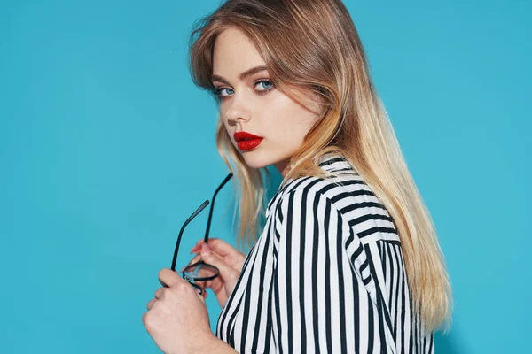 Mulher atraente vestindo óculos listrado camisa moda posando em fundo azul — Fotografia de Stock