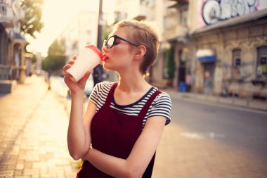 Dışarıda gözlüklü güzel bir kadın bir fincan kahve içti.