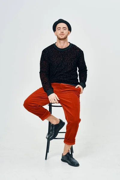 man in black sweater red pants posing studio self-confidence