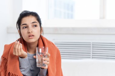 Battaniyeye sarılı bir kadın kanepeye oturur sağlık sorunları, soğuk muamele