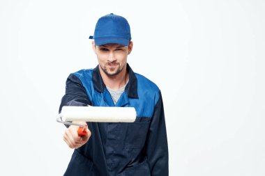 Çalışan üniformalı bir adam elleriyle duvarları boyayan bir silindir.
