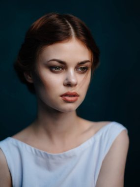 Beyaz elbiseli güzel bir kadın. Makyaj yüzü. Yakından poz veriyor.