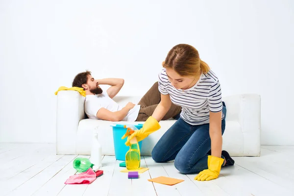 Una joven pareja cerca del sofá detergente trapos esponjas prestación de servicios — Foto de Stock