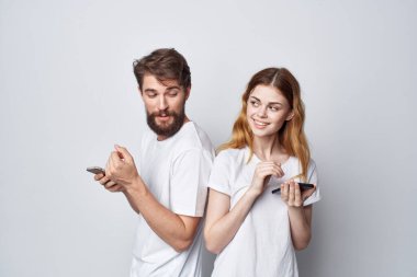 Beyaz tişörtlü erkek ve kadın ellerinde telefonlar stüdyo yaşam tarzı