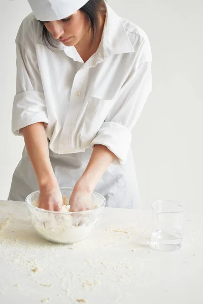 Mulher em chefs uniforme peneira farinha massa de trabalho na cozinha — Fotografia de Stock