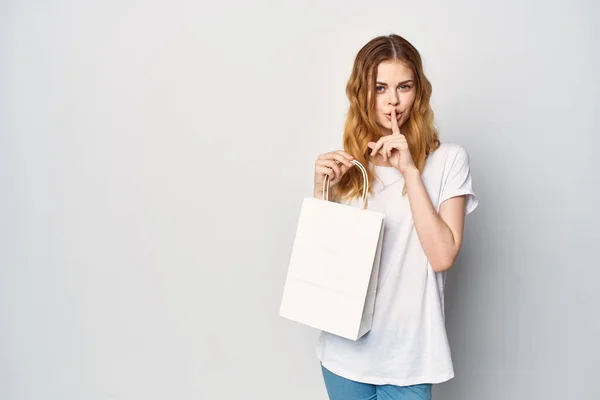흰색 티셔츠를 입고 쇼핑 가방을 들고 있는 예쁜 여성 — 스톡 사진