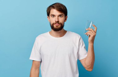 Beyaz tişörtlü bir adam, bir bardak su stüdyosu.