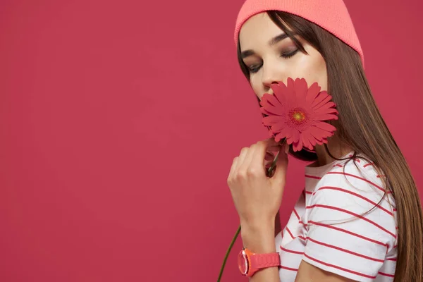 Brunette portant un chapeau rose fleur rouge maquillage décoration fond rose — Photo