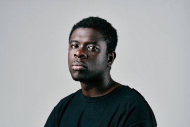 Siyah tişörtlü Afrikalı adam moda stüdyosunda yakın çekim pozu veriyor.