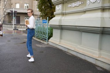 Kısa saçlı, gözlüklü, kitap eğitimi almış bir kadın.