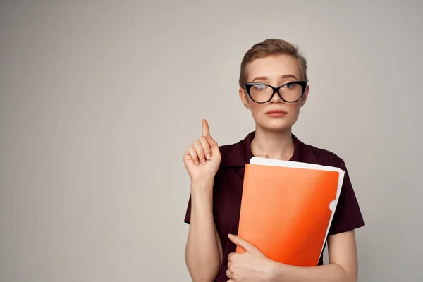 Mooie vrouw met een oranje map in de hand lichte achtergrond — Stockfoto