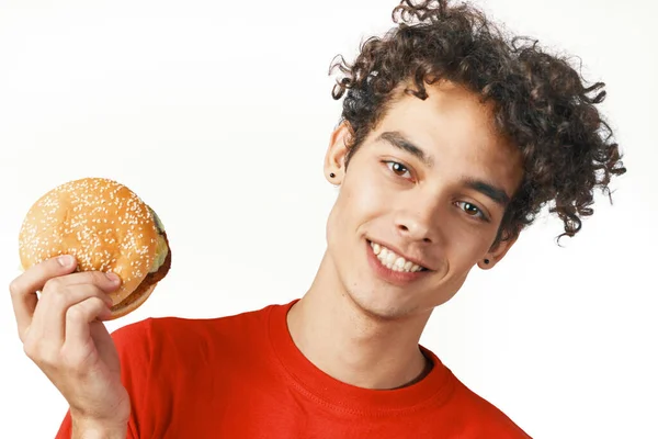 Alegre rizado hamburguesa chico sosteniendo un rojo camiseta estilo de vida — Foto de Stock