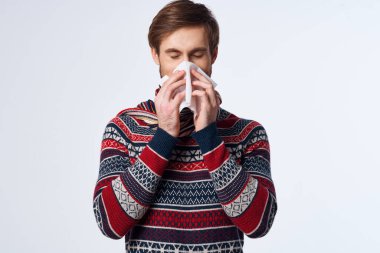 Duygusal bir adam mendil enfeksiyonuyla burnunu siliyor virüs arka planda.