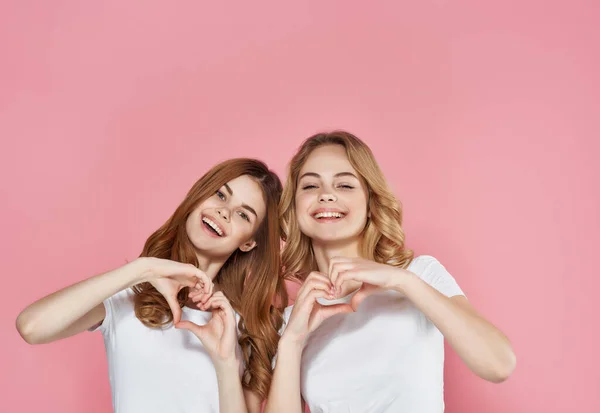 Donne in bianco t-shirt stand accanto alle emozioni amicizia rosa sfondo — Foto Stock