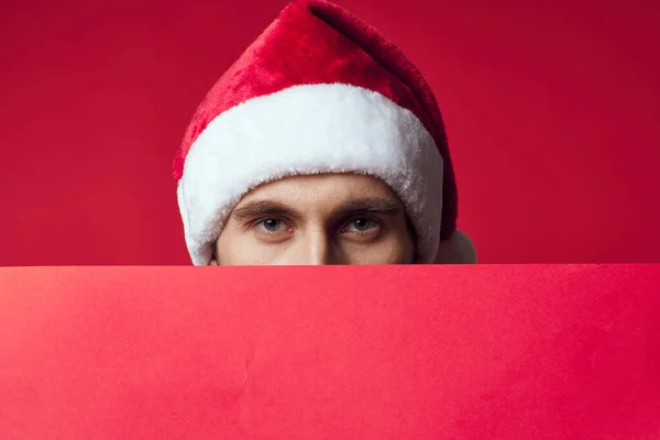 Przystojny mężczyzna w Santa kapelusz trzymając sztandar wakacje czerwony tło — Zdjęcie stockowe