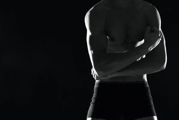 Sporty muscular man in black shorts bodybuilder dark background — Stock Photo, Image