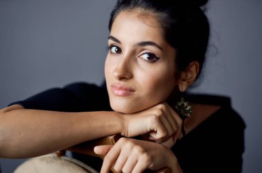 Güzel bir kadın, sandalyenin yanında duran küpeler siyah elbise yaşam tarzı stüdyosu.