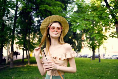 Güzel bir kadın. Parkta içkisi olan bir bardak. Yaşam tarzı.