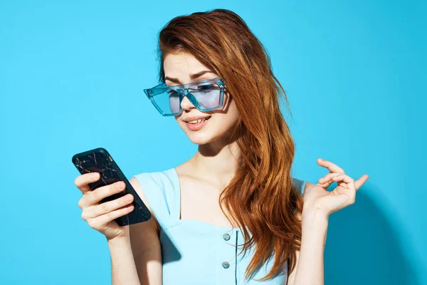 Mujer en un vestido azul con el teléfono en la mano posando estudio divertido —  Fotos de Stock