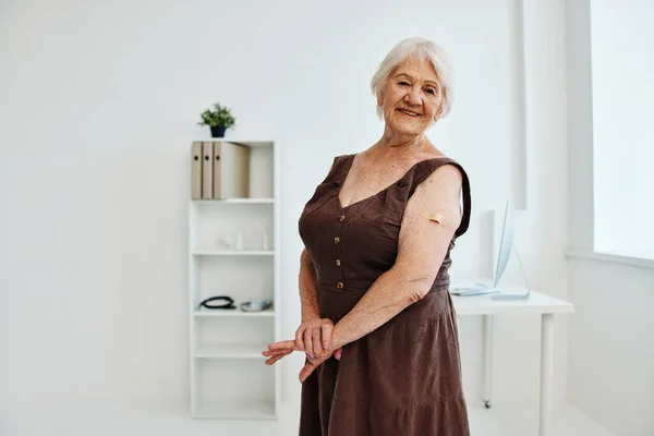 Alte Frau mit Pflaster am Arm Impfpass covid-19 — Stockfoto