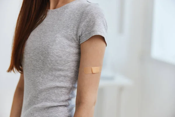 Žena s lepicí omítkou na rameni covid pas šedé tričko medicína nemocnice — Stock fotografie