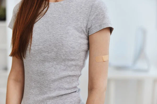 Kvinna t-shirt med självhäftande plåster på axeln immunitet hälsa covid pass — Stockfoto