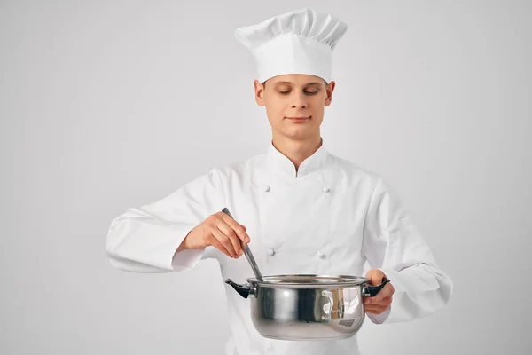 Man in chef-koks kleding met een steelpan in zijn handen het bereiden van voedsel lichte achtergrond — Stockfoto