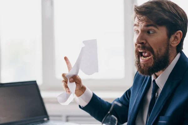 Bearded man sitting at a desk in front of a laptop stress anger — Stock Photo, Image