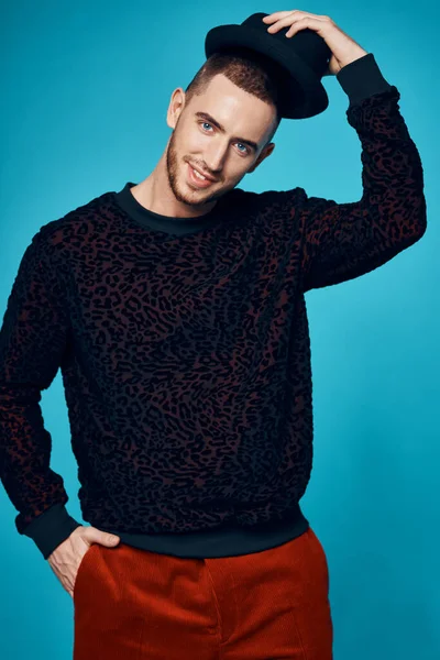 Mann in schwarzem Pullover Mützen posiert Mode-Studio blauen Hintergrund — Stockfoto