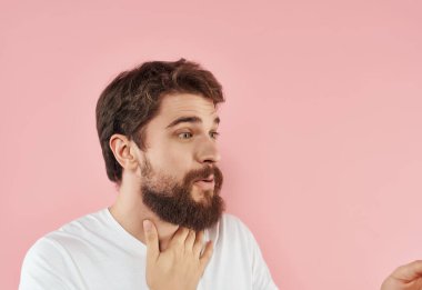 Beyaz tişörtlü, sakallı yakışıklı adam pembe arka plan duyguları.