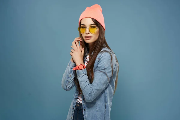 Mooie vrouw dragen bril moderne kleding denim jas blauwe achtergrond — Stockfoto