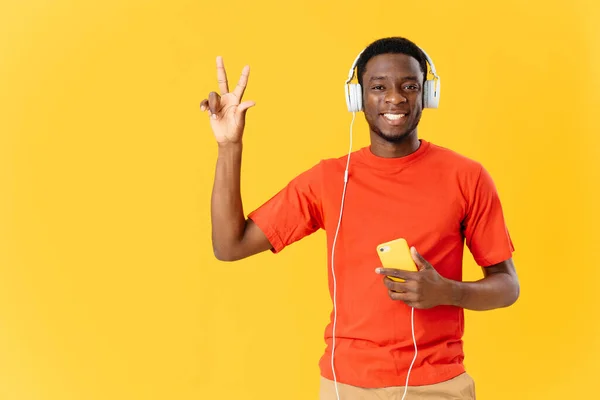 Sorridente homem africano usando fones de ouvido divertido fundo amarelo — Fotografia de Stock