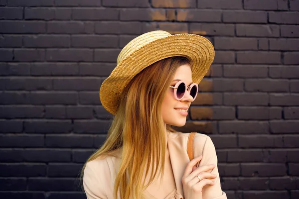 Atrakcyjna kobieta na ulicy w kapeluszu i okularach czarny mur z cegły — Zdjęcie stockowe
