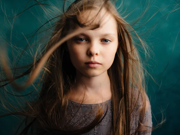 Malá dívka volné vlasy zelené pozadí nespokojenost emoce — Stock fotografie